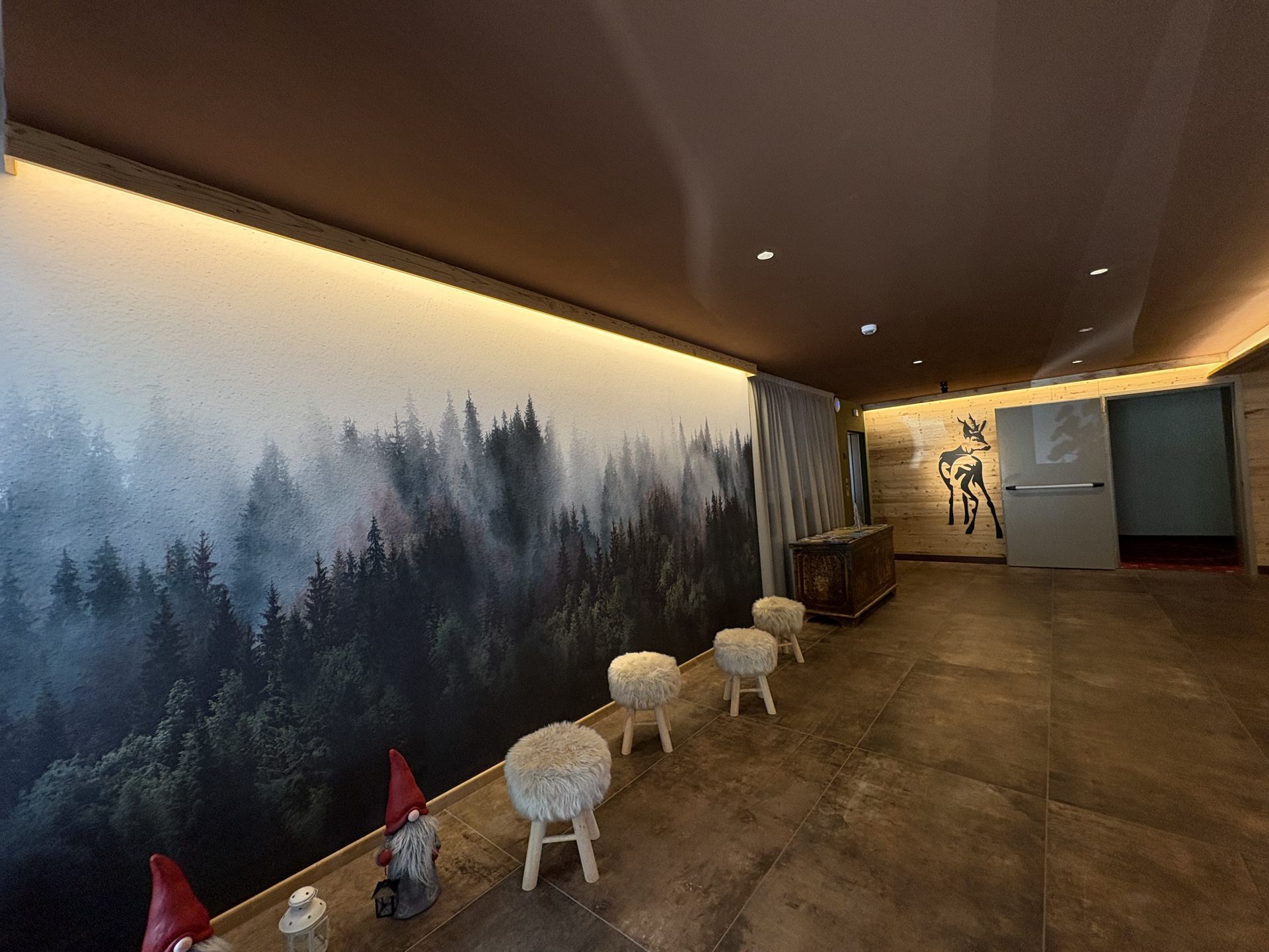 Il corridoio della hall con la parete del bosco e gli sgabelli in legno